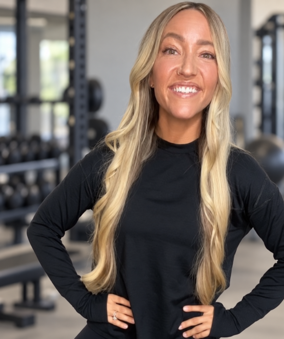 Amy Mason smiling in black athletic wear in a neutral gray gym